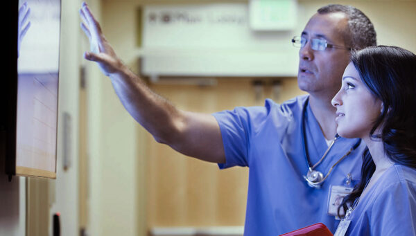Nurse looking at a whiteboard with a colleague